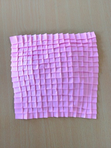 Pink sheet of pleated paper, folded as part of the workshop on paper pleating